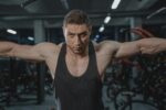 Focused man in activewear exercising in a gym environment.