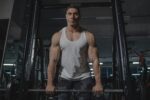 Male bodybuilder lifting weights during workout in gym. Intense focus and physical strength displayed.