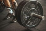 Close-up of a weightlifter's legs and barbell during a workout session.